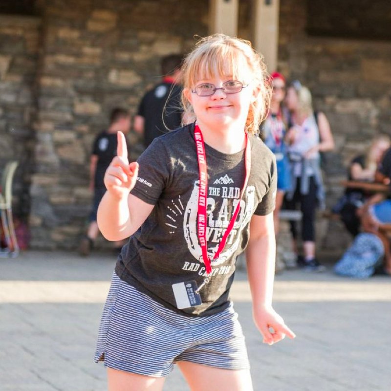 A young girl with blonde hair, glasses, and RAD West shirt dancing.