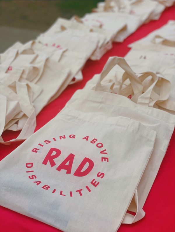 Image of a stack of reusable bags. The word RAD is in the middle with the pink words Rising Above Disabilities around it in a circle.