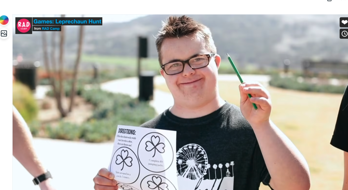 A man with Down Syndrome smiling and holding up a colored pencil and a Leprechaun Hunt printout