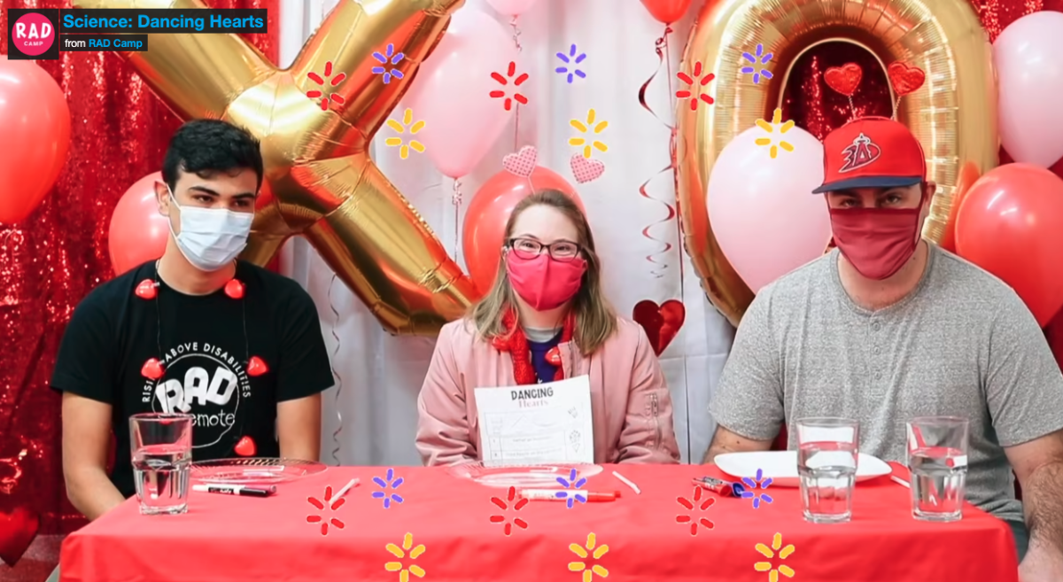 3 people at a Valentines decorated table with supplies for the science experiment.